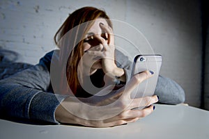 Young sad vulnerable girl using mobile phone scared and desperate suffering online abuse cyberbullying photo