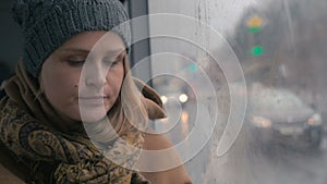 Young sad woman in the bus on a dull rainy day