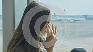 Young sad woman is crying at airport with airplane on the background