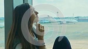 Young sad woman is crying at airport with airplane on the background