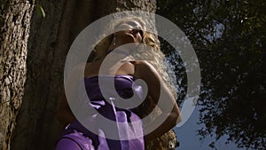 Young sad woman with curly blonde hair in elegant purple dress