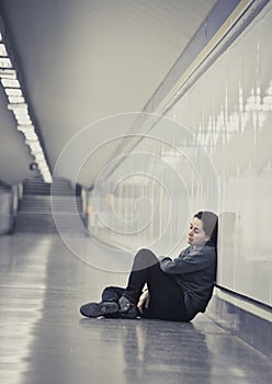 young sad woman in pain alone and depressed at urban subway tunnel ground worried suffering depression