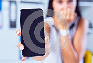 Young sad woman showing a blank smartphone screen. Focus on smartphone. Free space for your message.