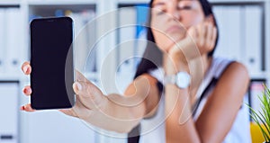 Young sad woman showing a blank smartphone screen. Focus on smartphone. Free space for your message.