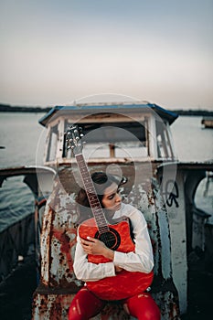 A young woman sits with guitar on old abandoned ship
