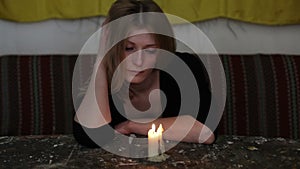 Young sad woman sitting with a candle