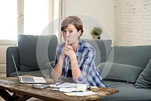 Young sad worried and desperate woman banking and accounting home monthly and credit card expenses with computer laptop