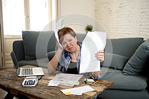 Young sad worried and desperate woman banking and accounting home monthly and credit card expenses with computer laptop