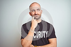 Young safeguard man wearing security uniform over isolated background with hand on chin thinking about question, pensive