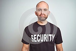 Young safeguard man wearing security uniform over isolated background puffing cheeks with funny face