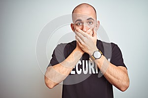 Young safeguard man wearing security uniform over isolated background shocked covering mouth with hands for mistake