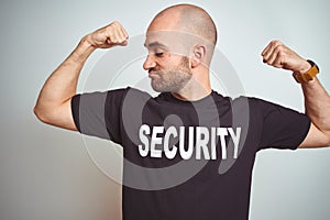 Young safeguard man wearing security uniform over isolated background showing arms muscles smiling proud