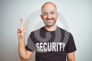 Young safeguard man wearing security uniform over isolated background showing and pointing up with fingers number two while