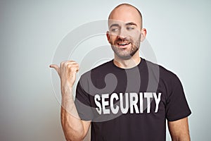 Young safeguard man wearing security uniform over isolated background smiling with happy face looking and pointing to the side