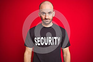 Young safeguard man wearing security uniform over red isolated background with serious expression on face