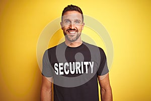 Young safeguard man wearing security uniform over yellow isolated background with a happy and cool smile on face