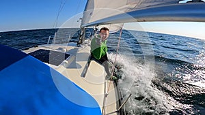 Young sailor managing sails on Sailboat in open, rough and wavy sea. travel, adventure concept