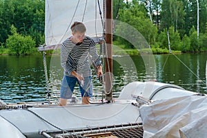 Young sailor raises sail on a small sailing catamaran