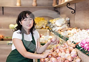 Young salesgirl at her first job, selling onions in vegetable shop
