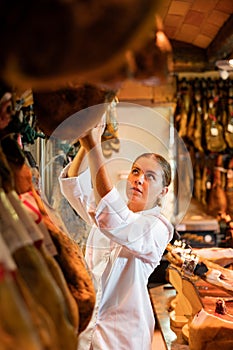 Young salesgirl working in butcher shop specializing in sale of Iberian jamon