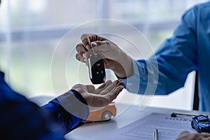 Young salesman holding car keys in hands of car rental business customer sell