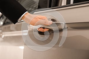 Young salesman in suit opening car door, closeup