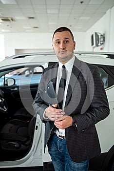 young salesman in suit waiting for customer at the dealership. purchase car concept