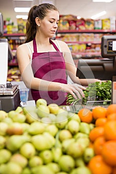 Young saleswoman weighs greens on a scale