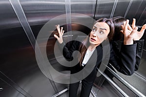 young scared businesswoman suffering from claustrophobia in elevator.