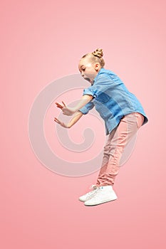 Young scared caucasian teen girl jumping in the air, on pink studio background.