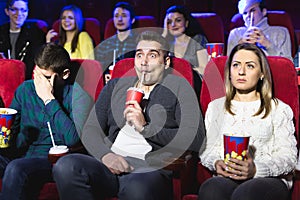 Young scared couple at the cinema watching an horror movie.