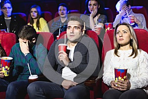 Young scared couple at the cinema watching an horror movie.