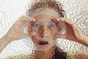 Young scared girl behind glass with her hands on it