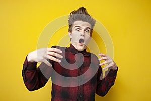 Scared guy is surprised and screaming on yellow isolated background, shocked man in stress