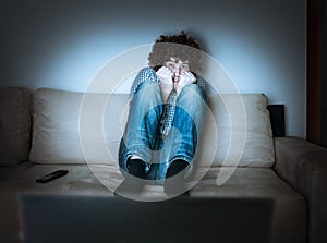 Young scared man is watching horror or thriller on TV photo
