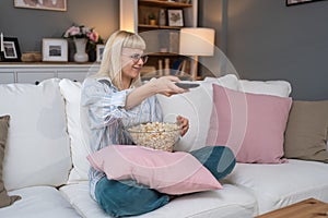 Young scared woman sitting alone at home on the floor watching scary horror movie on the television. Disgusted animal lover female