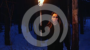 Young scared woman with torch running from something and looking in the camera