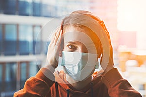 Young scared woman wearing surgical mask because of viruses and air pollution in the city photo
