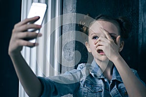 Young scared and worried teenager girl holding mobile phone as internet stalked victim abused and cyberbullying or cyber