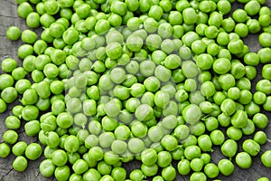 Young scattered green peas on a wooden background,