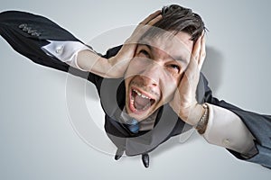 Young schizophrenic man suffers from headache and covering his ears with hands