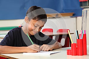 Young school boy 10 writing at his classroom desk