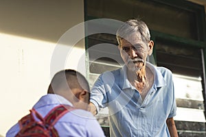 A young school boy pays respect to his grandfather by doing the mano po gesture. Filipino culture photo