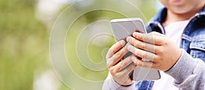 Young school boy texting outdoor. Male person using smartphone. Little hands