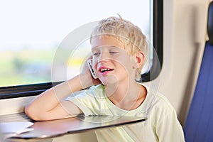 Young school boy in train with mobile phone