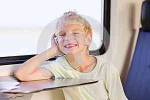 Young school boy in train with mobile phone