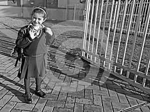 Young school girl waving goodbye before entering school