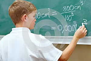 Hes a junior genius. Young schoolboy doing an equation on the blackboard at school.