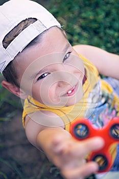 Young schoolboy holding popular fidget spinner toy - close up portrait. Happy smiling child playing with Spinner.