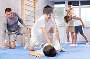 Young schoolboy practicing basic self-defense moves during training, practicing painful pronating wristlock on opponent